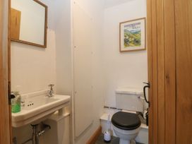 A small bathroom with a toilet and sink a mirror above the sink and a framed picture on the wall at Priddbwll in Llansannan