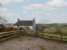 A countryside house with a tiled roof near a wooden fence and open fields at Priddbwll in Llansannan