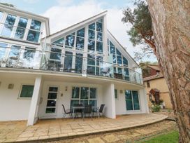 A modern two-story house with large triangular windows and a glass balcony railing at 5 Red Sails in Sandbanks