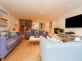 A living room with three sofas a coffee table a wall mounted television and stairs at 5 Red Sails in Sandbanks