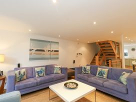 A living room with two blue sofas and a white coffee table by a wooden staircase at 5 Red Sails in Sandbanks