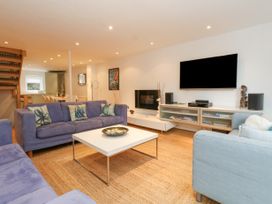 A living room with blue sofas a white coffee table a wall-mounted TV and shelving at 5 Red Sails in Sandbanks