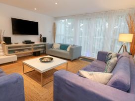 A living room with two blue sofas one gray sofa a white coffee table and a wall mounted television at 5 Red Sails in Sandbanks