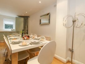 A dining area with a set table and chairs next to a kitchen in 5 Red Sails in Sandbanks