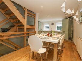 A dining area with a table set for meals and modern chairs near a staircase at 5 Red Sails in Sandbanks