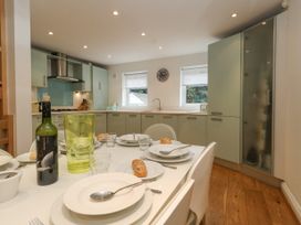 A kitchen with light green cabinets a dining table set with plates cutlery and bread at 5 Red Sails in Sandbanks
