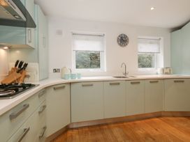 A kitchen with light green cabinets a white countertop a sink a kettle mugs a knife block and a toaster at 5 Red Sails in Sandbanks