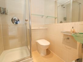 A bathroom with a shower, toilet, glass sink, and wall-mounted shelves at 5 Red Sails in Sandbanks