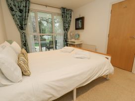 A bedroom with a bed folded towels a desk fan a mirror wooden door and glass sliding doors at 5 Red Sails in Sandbanks