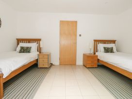 A bedroom with two single beds with white bedding and wooden headboards and two wooden bedside tables with lamps at 5 Red Sails in Sandbanks