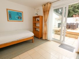 A bedroom with a single bed a wooden shelf a curtain and sliding glass doors leading to a patio at 5 Red Sails in Sandbanks