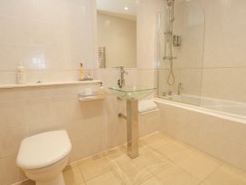 A bathroom with a toilet a glass sink and a bathtub with a shower at 5 Red Sails in Sandbanks
