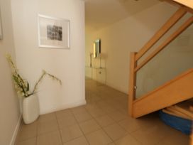 A hallway with a staircase to the right a vase with flowers on the floor and framed artwork on the wall at 5 Red Sails in Sandbanks
