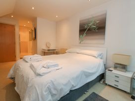 A bedroom with a made bed and folded towels on it next to a bedside table with a lamp and a dressing table with a mirror at 5 Red Sails in Sandbanks