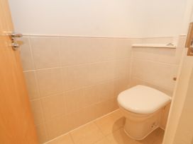 A small bathroom with a closed white toilet and beige tiled walls and floor at 5 Red Sails in Sandbanks