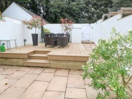 An outdoor patio area with stone paving wooden deck with steps dining table and chairs potted plants and white walls at 5 Red Sails in Sandbanks