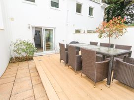 An outdoor patio area with a large glass table and eight wicker chairs at 5 Red Sails in Sandbanks