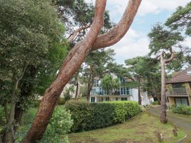 A garden area with trees and bushes in front of residential buildings at 5 Red Sails in Sandbanks