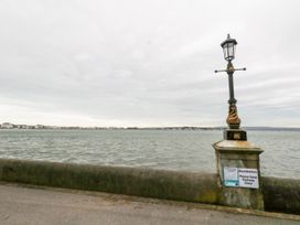 A waterfront with a stone railing and a decorative lamp post with signs at 5 Red Sails in Sandbanks