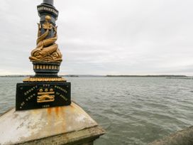 A decorative post with fish carvings overlooking water with distant land on the horizon at 5 Red Sails in Sandbanks