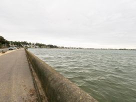 A road and seawall alongside a body of water with buildings in the distance at 5 Red Sails in Sandbanks