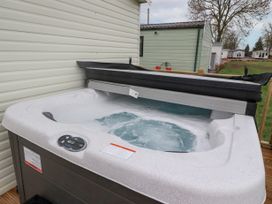 An outdoor hot tub with bubbling water next to a white sided building at Larenzo in Warton Lancashire