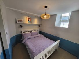 A bedroom with a bed and wall art at Fishermans Locker in West Bay