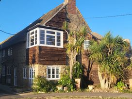 A house with windows and palm trees at Fishermans Locker in West Bay