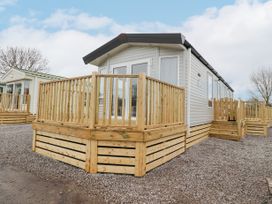 A static caravan with wooden decking and steps on a gravel surface at Giorgio in Warton Bank near Warton Lancashire