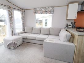A living room with a grey sectional sofa and ottoman near windows at Giorgio in Warton Bank near Warton Lancashire
