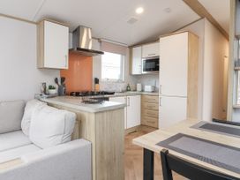A kitchen with wooden cabinets white cupboards a microwave stove and dining table with placemats at Giorgio in Warton Bank near Warton Lancashire