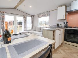 A kitchen and living area with dining table glasses and bottle on table at Giorgio in Warton Bank near Warton Lancashire
