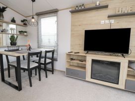 A dining area with a table and chairs next to a TV and electric fireplace at Giorgio Warton Bank near Warton Lancashire