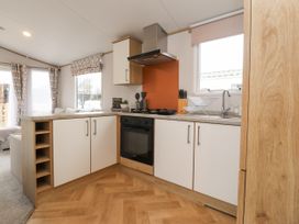 A kitchen with cabinets a stove a sink and windows at Giorgio in Warton Bank near Warton Lancashire