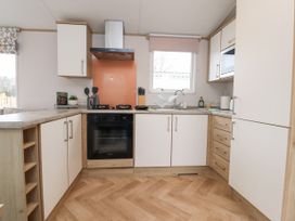 A kitchen with white cabinets wood accents a gas stove oven dish rack and window at Giorgio in Warton Bank near Warton Lancashire