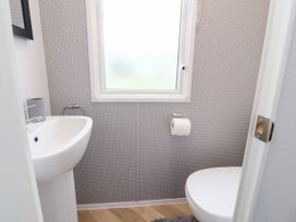 A bathroom with a sink toilet toilet paper holder and window at Giorgio Warton Bank near Warton Lancashire