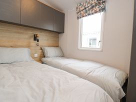 A bedroom with two single beds a window with patterned blinds and wall cabinets above the beds at Giorgio Warton Bank near Warton Lancashire