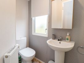 A small bathroom with a toilet a pedestal sink a window with a roller blind and a mirror cabinet at Giorgio in Warton Bank near Warton Lancashire