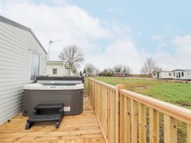 A wooden deck with a hot tub next to a mobile home and other mobile homes in the background at Giorgio in Warton Bank near Warton Lancashire