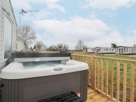 An outdoor hot tub on a wooden deck with multiple mobile homes in the background at Giorgio in Warton Bank near Warton Lancashire