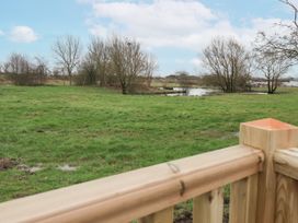 A field with grass trees and a small pond viewed from a wooden deck at Giorgio in Warton Bank near Warton Lancashire