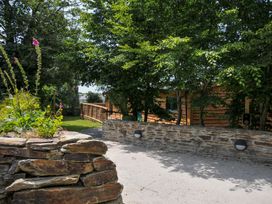 An outdoor area with a stone wall and wooden structure at Owl Lodge in Menheniot
