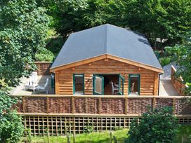 A log cabin with a deck and chairs at Owl Lodge Menheniot