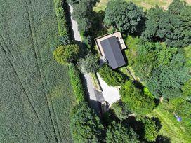 An aerial view of a house surrounded by trees and a road at Owl Lodge in Menheniot