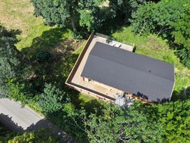 An aerial view of a building with a deck surrounded by trees at Owl Lodge in Menheniot