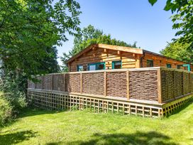 A house with a decking area and fence at Owl Lodge in Menheniot