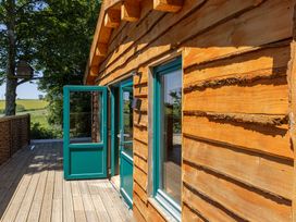 An exterior view of a cabin with an open door and wooden wall at Owl Lodge in Menheniot
