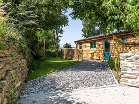 An outdoor area with a gravel pathway leading to a house at Owl Lodge in Menheniot