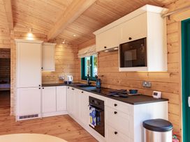 A kitchen with cabinets and appliances at Owl Lodge in Menheniot