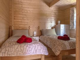 A bedroom with two beds and a dresser at Owl Lodge in Menheniot